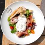 Listový šalát s burratou a prosciuttom, cherry rajčiny, vinaigrette, chrumkavé toasty
